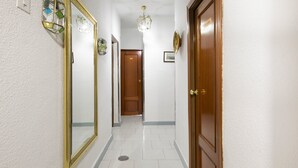 Un pasillo con una puerta de madera, un espejo y una lámpara.