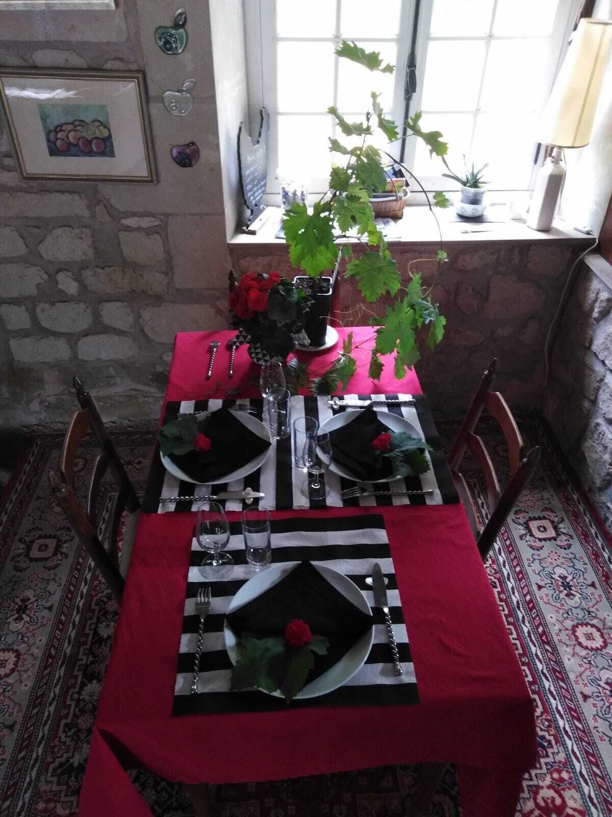 Une table à manger dressée avec des nappes noires et blanches, des serviettes rouges et un centre de table composé de roses rouges.