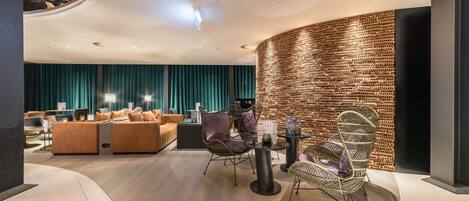 A modern interior with a curved seating area, a brick wall, and a ceiling with a unique pattern.