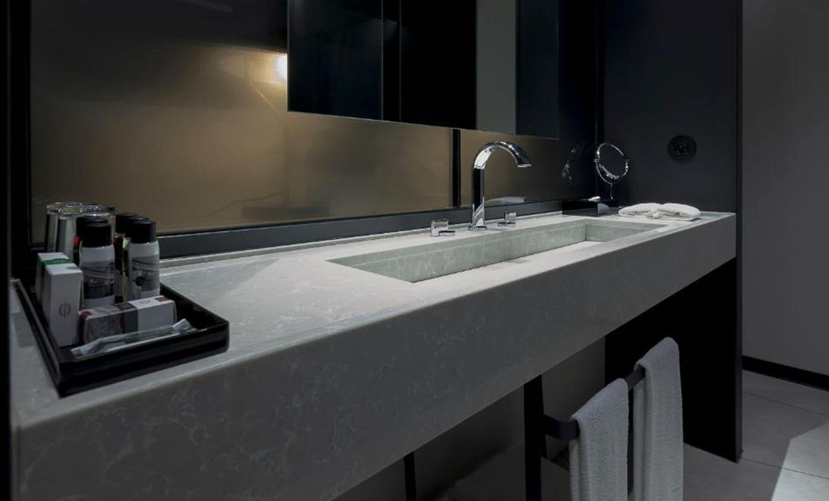 A modern bathroom with a large mirror, two sinks, and a tray with toiletries.