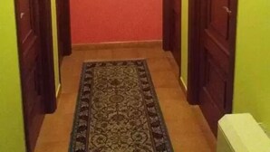 A hallway with a patterned rug, wooden doors, and a framed picture on the wall. - Pension Restaurante Vazquez (Vimianzo)