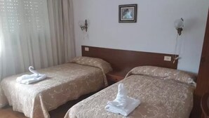Two twin beds with matching headboards and footboards, each with a folded white towel on the bed. - Pension Restaurante Vazquez (Vimianzo)