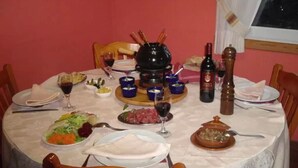 A dining table set with various dishes, wine glasses, and a central hot pot. - Pension Restaurante Vazquez (Vimianzo)