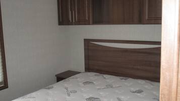 A small bedroom with a single bed, wooden headboard, and built-in wooden cabinets above the bed.