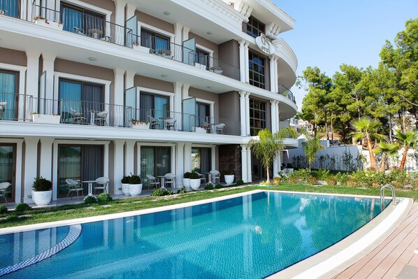 Un hotel de varios pisos con piscina, mobiliario exterior y un jardín bien cuidado.