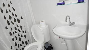 A bathroom with a toilet, sink, and a shower curtain with a unique pattern.