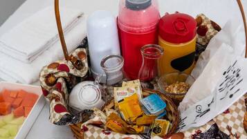 A variety of food items and containers, including a basket with snacks, a jar of honey, and several bottles.