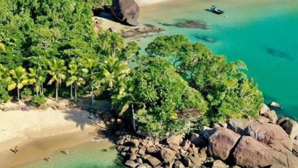 Une plage tropicale aux eaux turquoise et limpides, bordée d’une côte rocheuse et d’une végétation luxuriante.