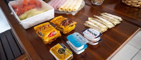 Un bufé de desayuno con diversos alimentos, incluyendo frutas, carnes, quesos y salsas.