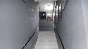 Un escalier avec des rampes, des murs carrelés et des affiches accrochées au mur.