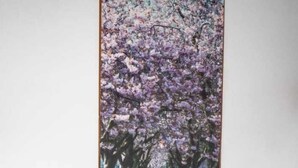 Une table à manger avec des chaises et un tableau représentant un chemin bordé d’arbres en fleurs, aux couleurs roses.
