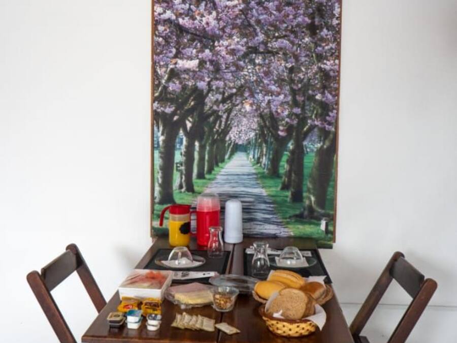 Una mesa de comedor con sillas, un cuadro de un árbol de cerezos y diversos alimentos.