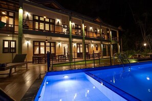 A two-story hotel with a swimming pool, outdoor seating, and a well-lit balcony. - Huluganga Ridge (Teldeniya)