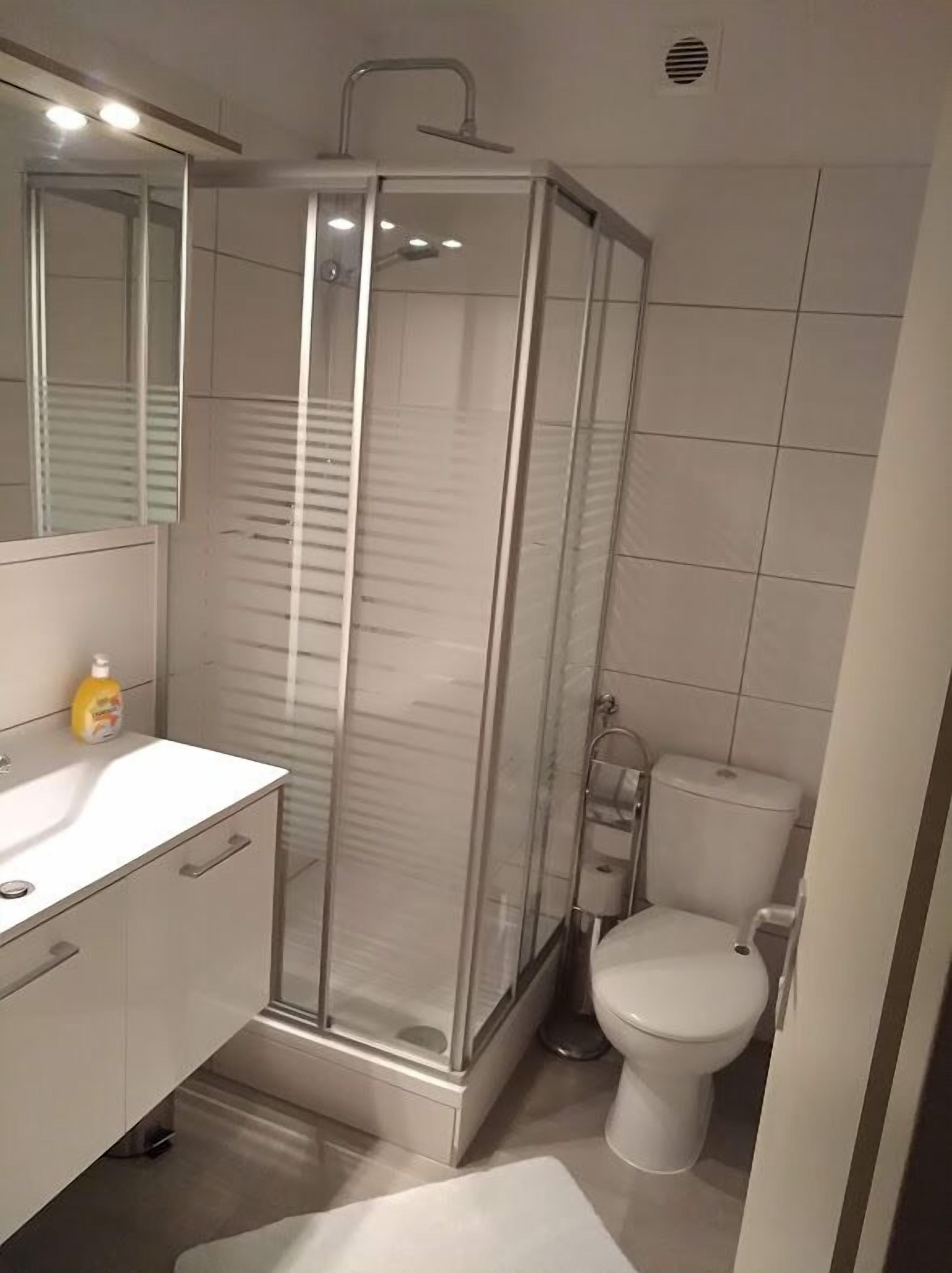 Une salle de bain moderne avec une douche à parois de verre, un lavabo blanc et des toilettes.