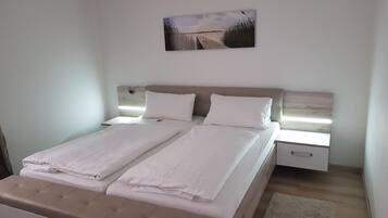 A double bed with a wooden headboard, two bedside tables, and a wall-mounted picture.