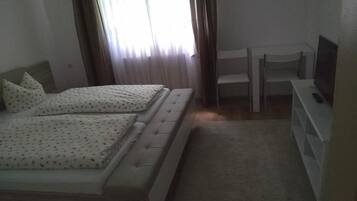 A bedroom with two beds, a TV, and a chair.