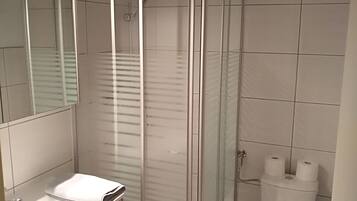 A modern bathroom with a glass-enclosed shower, a white sink, and a toilet.