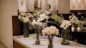 A marble countertop with multiple glass vases containing white flowers. - Hotel Leon (León)