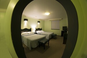 Habitación de hotel con dos camas, un escritorio, una silla, un televisor y una ventana.