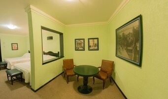 Una habitación de hotel con una cama, dos sillas, una mesa y tres cuadros colgados en la pared.