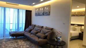 A modern living room with a sofa, a round coffee table, and a view of a bedroom. - Sky D'Mont Suites (Genting Highlands)