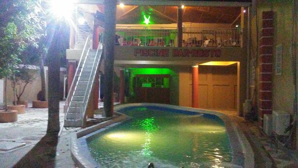 An indoor swimming pool with a ladder leading to a bar area.