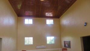 A room with a high ceiling, a gate with a view of the outside, and a wall-mounted air conditioning unit.