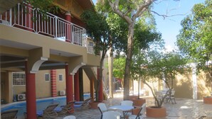 A courtyard with outdoor seating, a pool, and a covered area with red pillars.