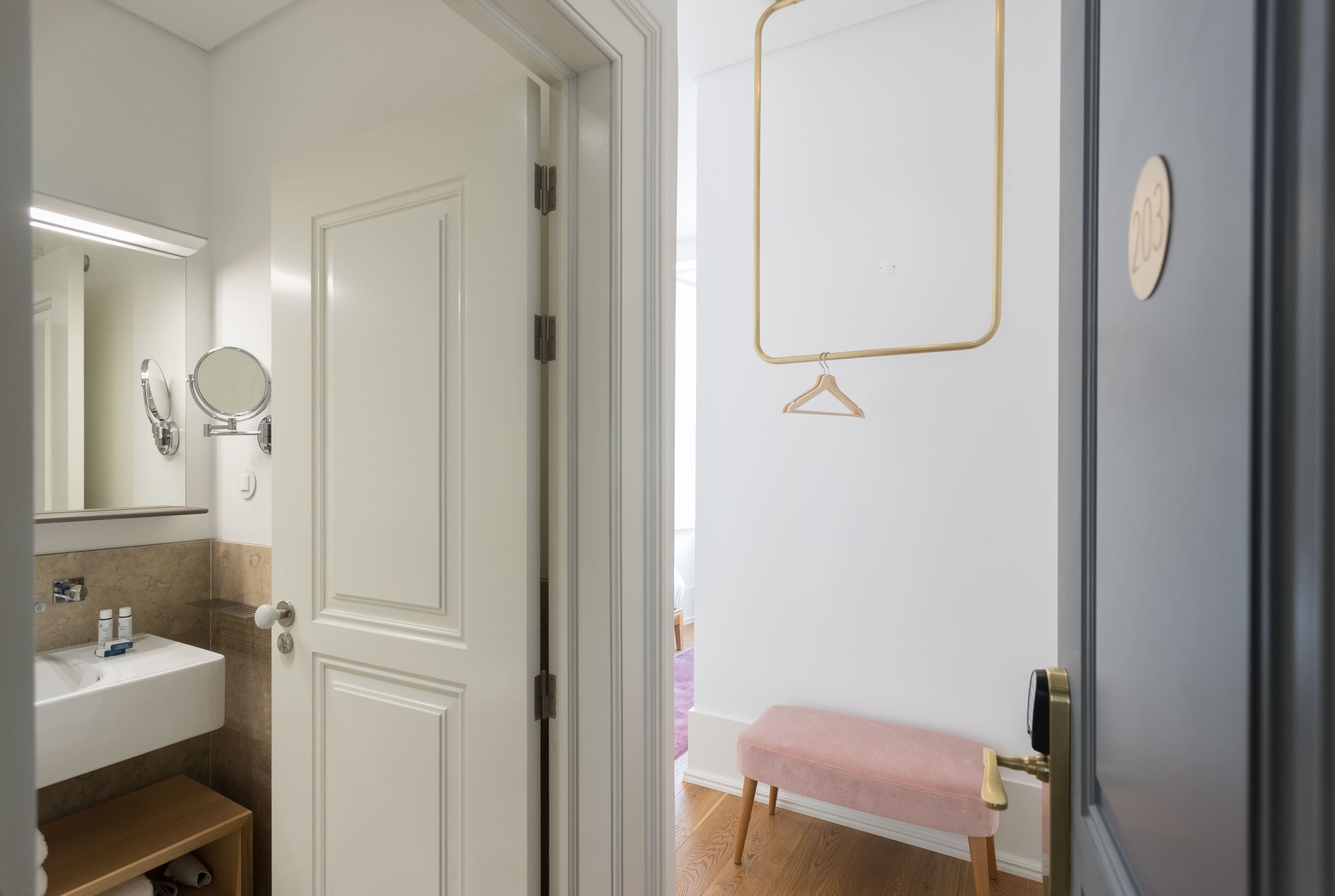 A bathroom with a white sink, mirror, and a bench.