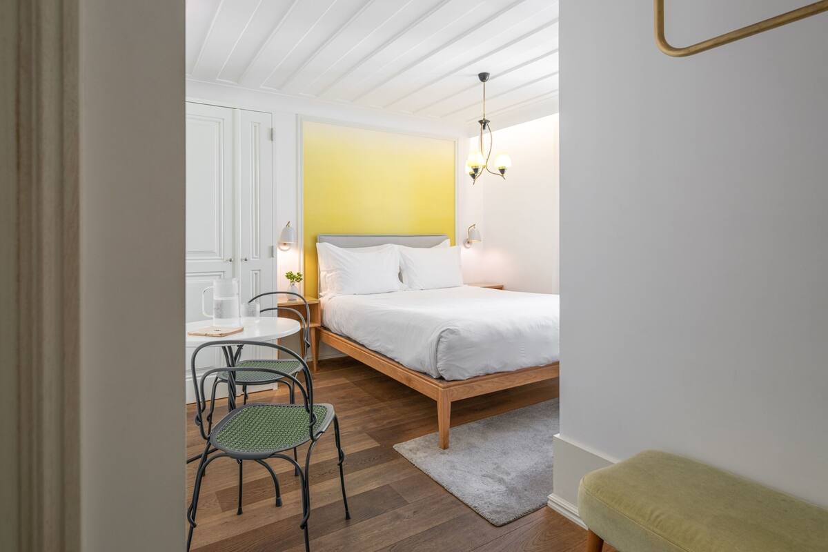 Une chambre à coucher avec un lit, un banc, une chaise et une petite table.