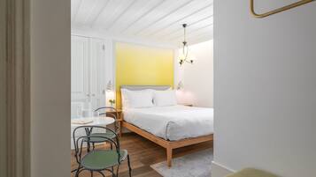 Een slaapkamer met een bed, een bankje, een stoel en een tafeltje.