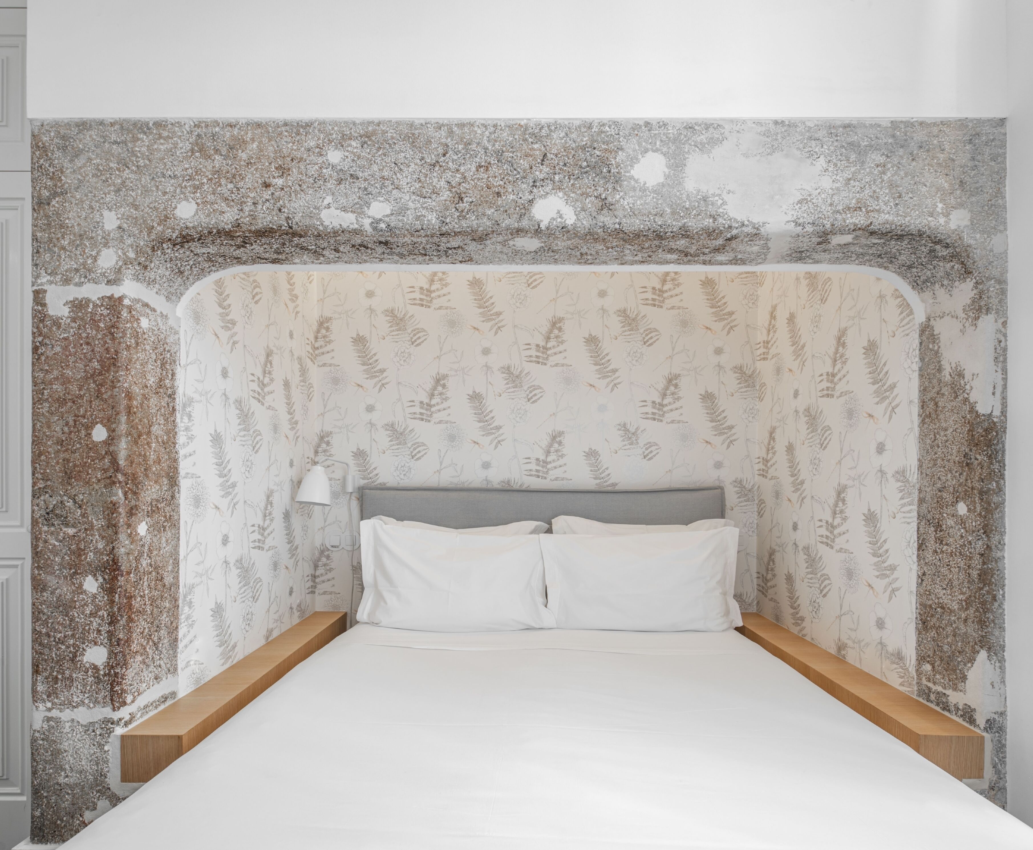 Un dormitorio con una cama, cabecera, mesita de noche y lámpara.