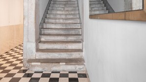 A staircase with a checkered floor, white walls, and a mirror reflecting the staircase.