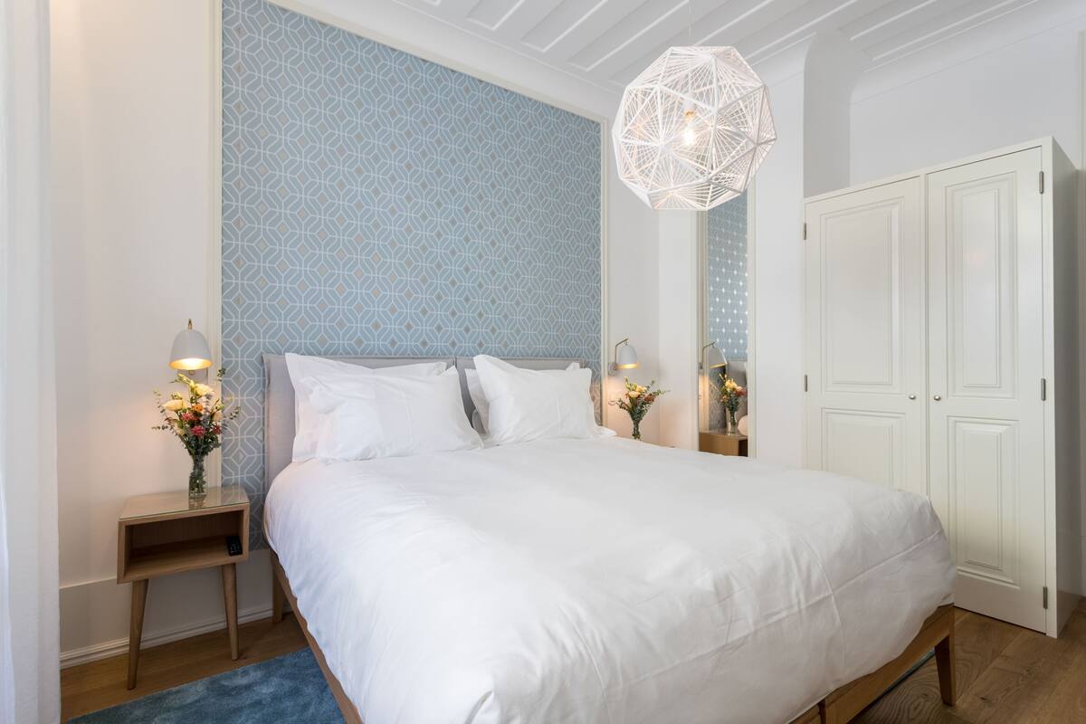 Une chambre à coucher avec un grand lit, une table de chevet avec une lampe, un mur décoratif et une armoire.