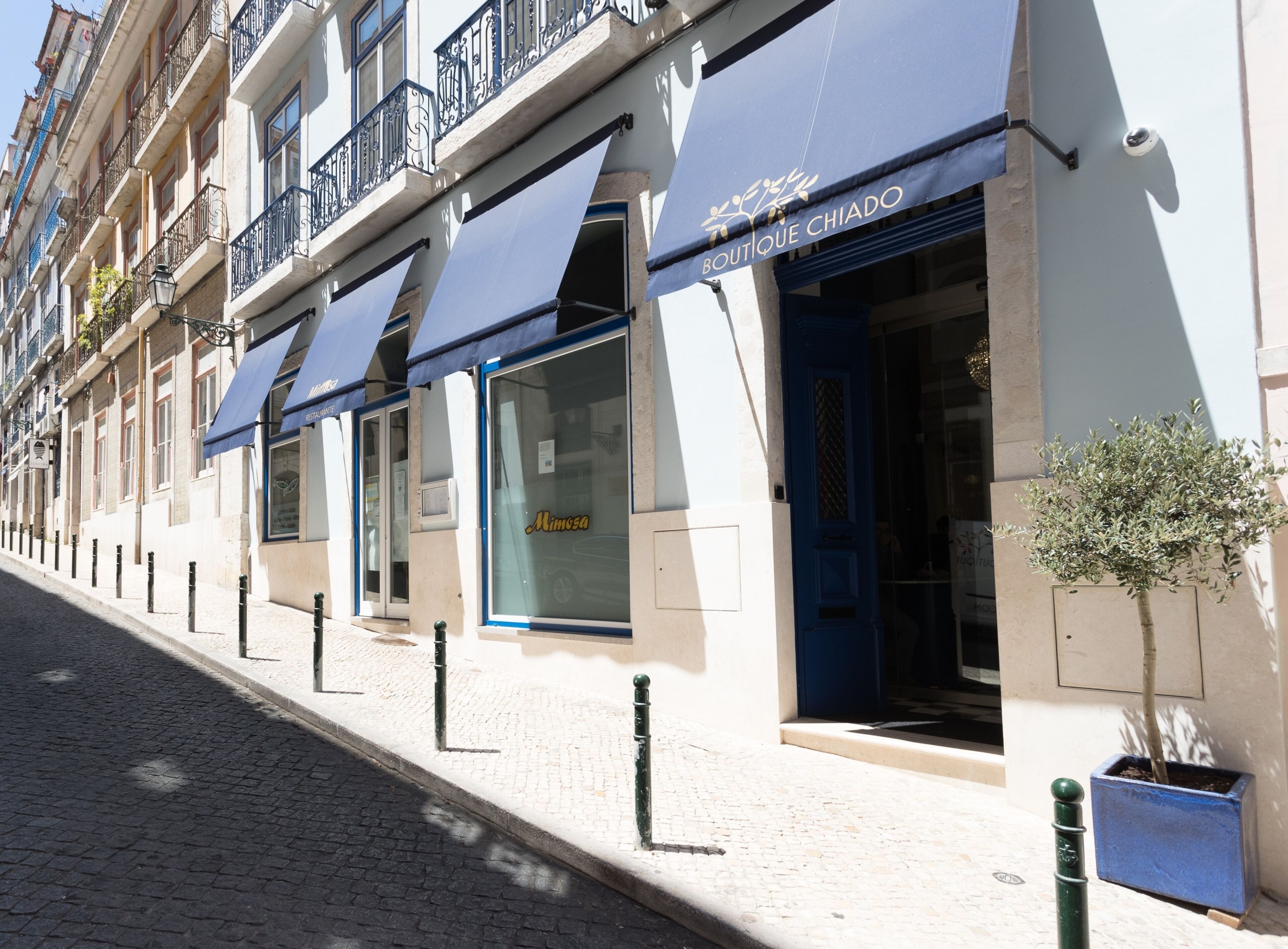 Une rangée de boutiques élégantes, toutes dotées d’auvents bleus, bordant une rue pavée.
