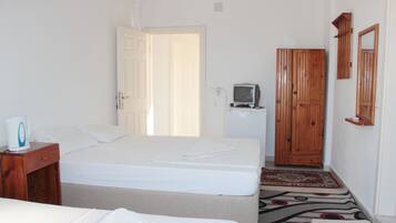 Een hotelkamer met een bed, een kleine televisie, een houten garderobe en een nachtkastje met een lamp.