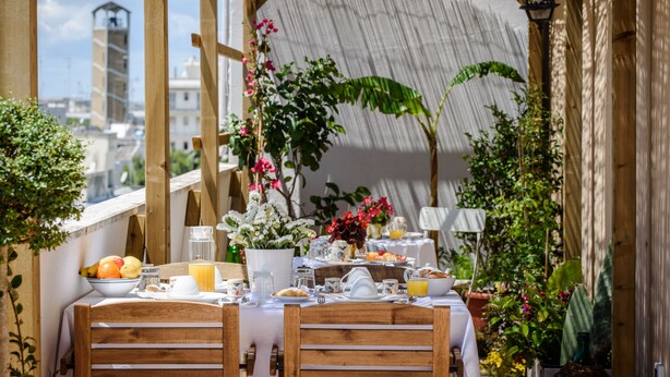 Ein Frühstückstisch mit Holzstühlen, umgeben von Blumentöpfen und Blumen.