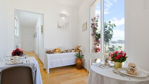 Ein Essbereich mit einem für das Frühstück gedeckten Tisch, einer Topfpflanze und einem Fenster mit Blick auf den Himmel.