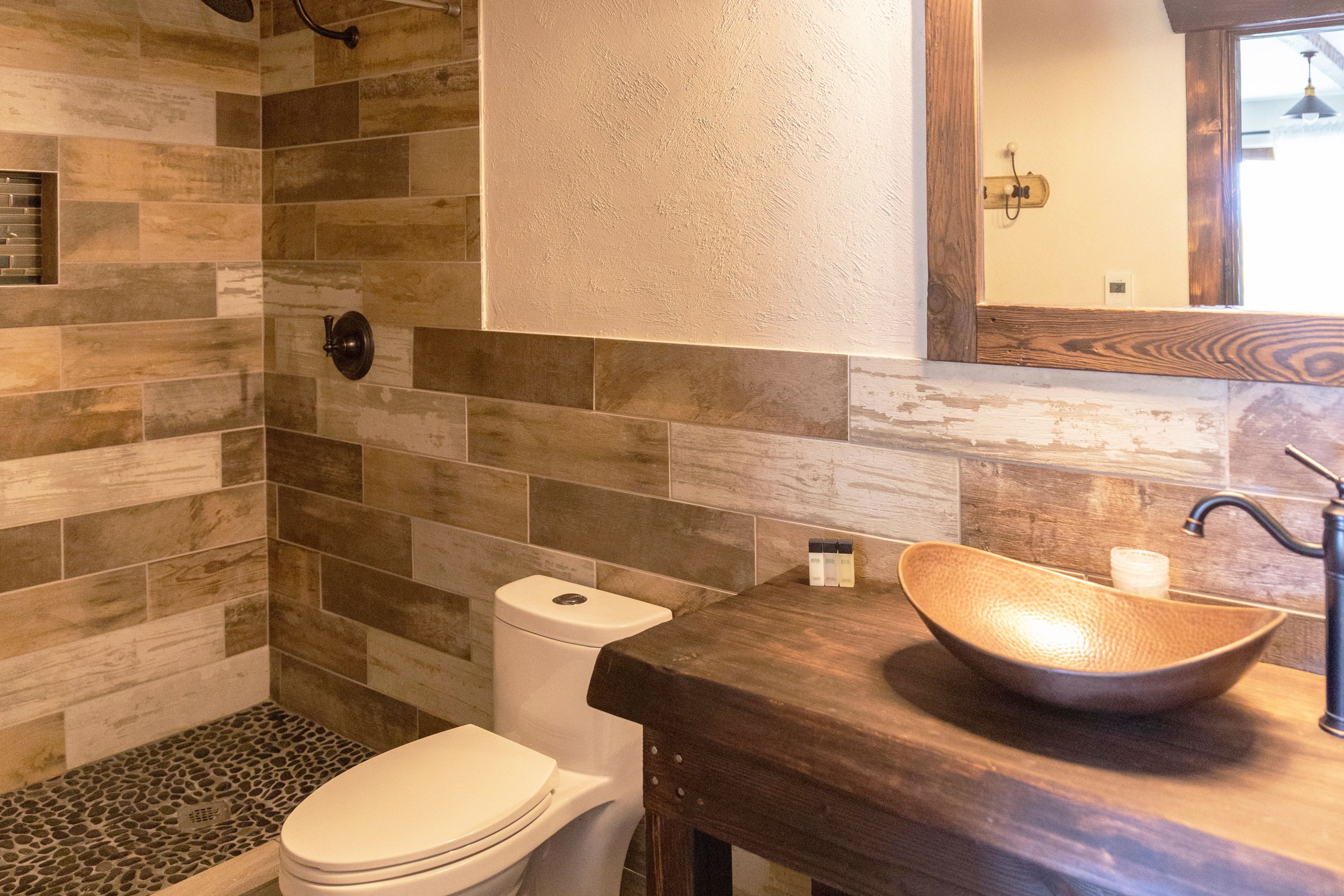 A bathroom with a wooden vanity, a vessel sink, and a toilet.