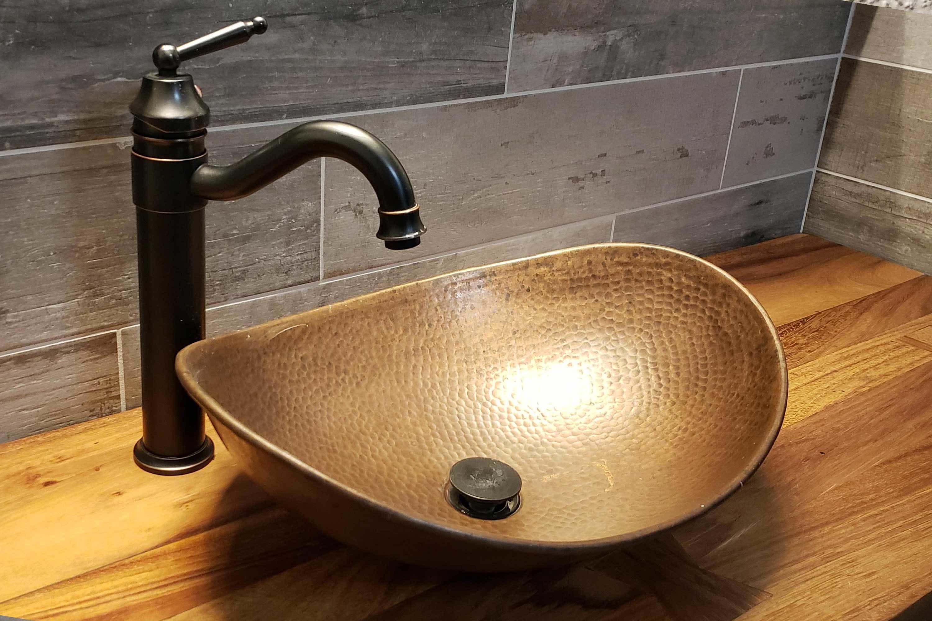A modern bathroom with a vessel sink, a black faucet, and a textured basin.