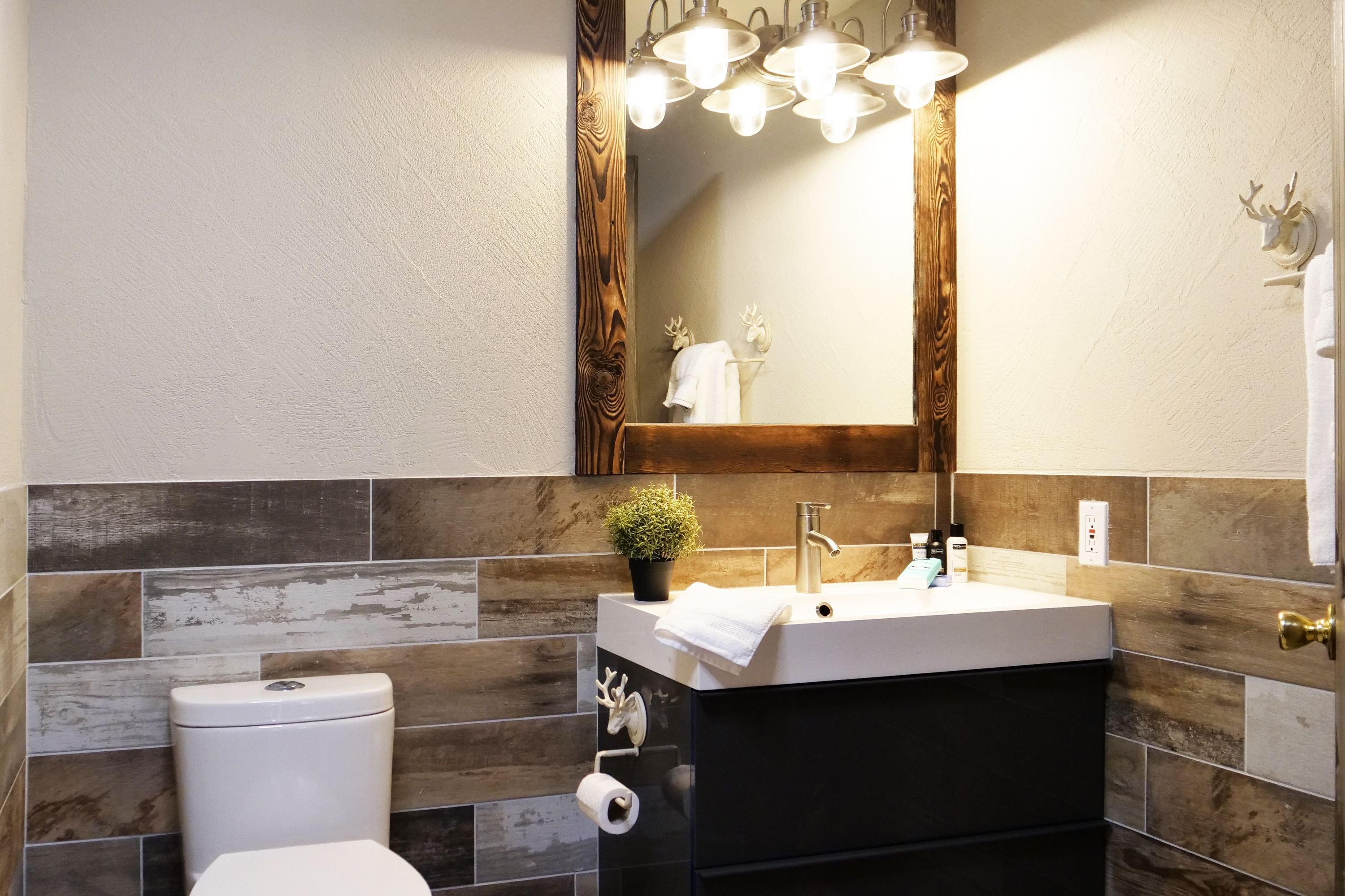 Un baño con inodoro blanco, lavabo con espejo y un perchero para toallas.