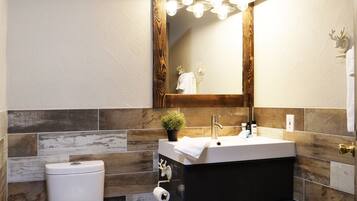 A bathroom with a white toilet, a sink with a mirror above, and a towel rack.