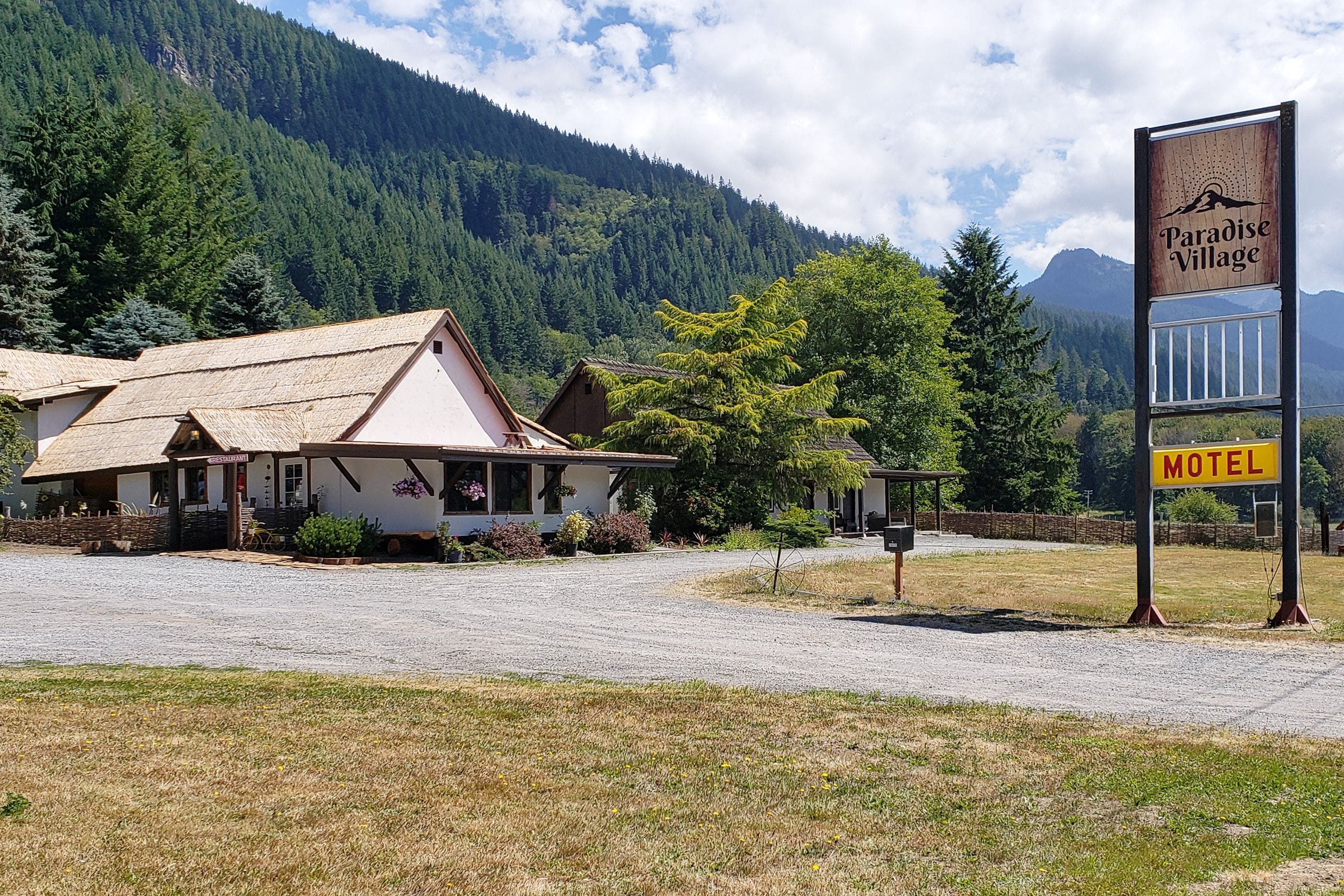 A motel named Paradise Village with a rustic building and a signboard.