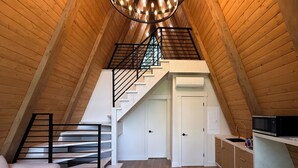 A loft-style room with a wooden ceiling, a staircase, a kitchen area, and a seating area. - Paradise Village Hotel (Ashford)
