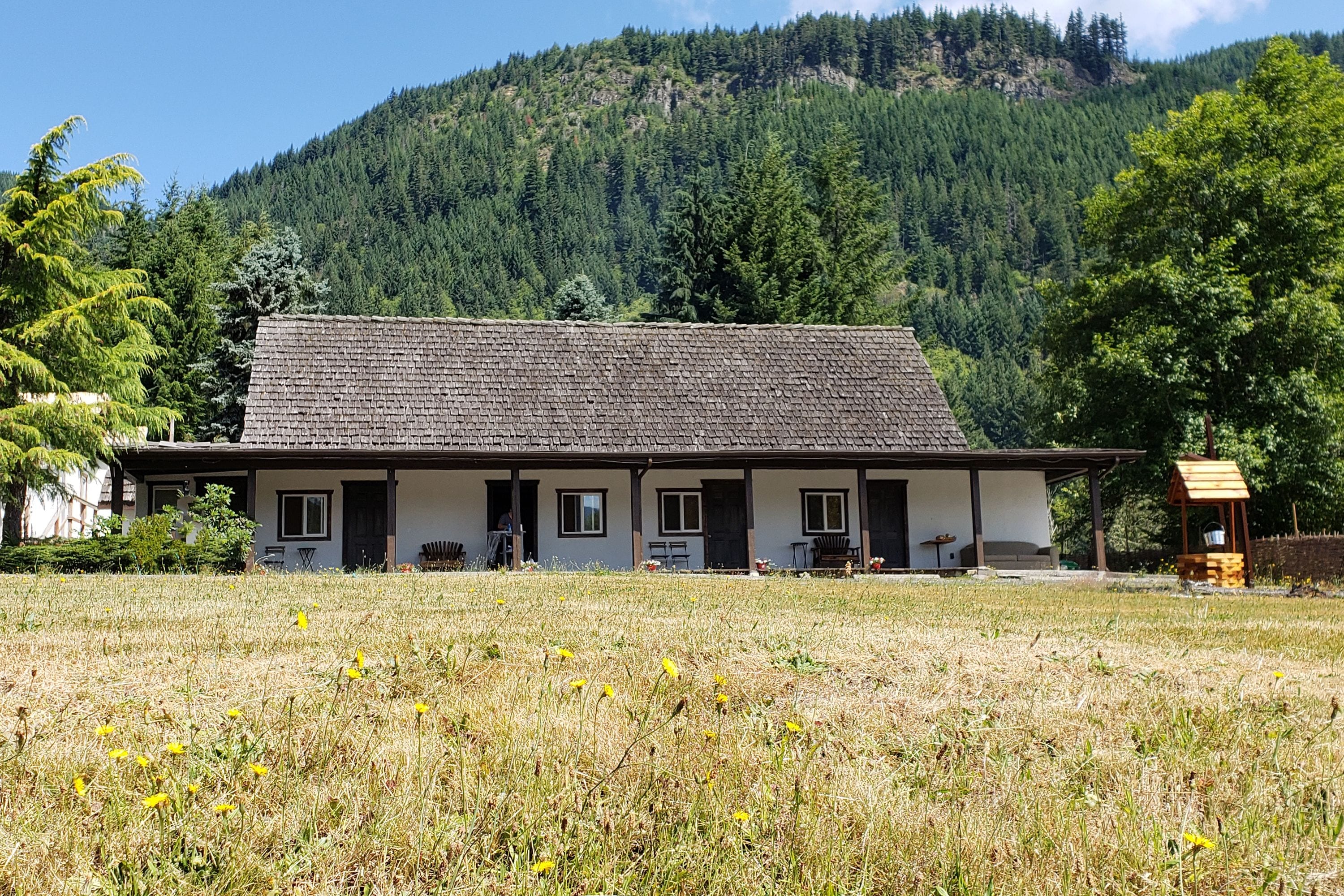 A two-story building with a sloped roof, a front porch, and a small wooden structure to the right.