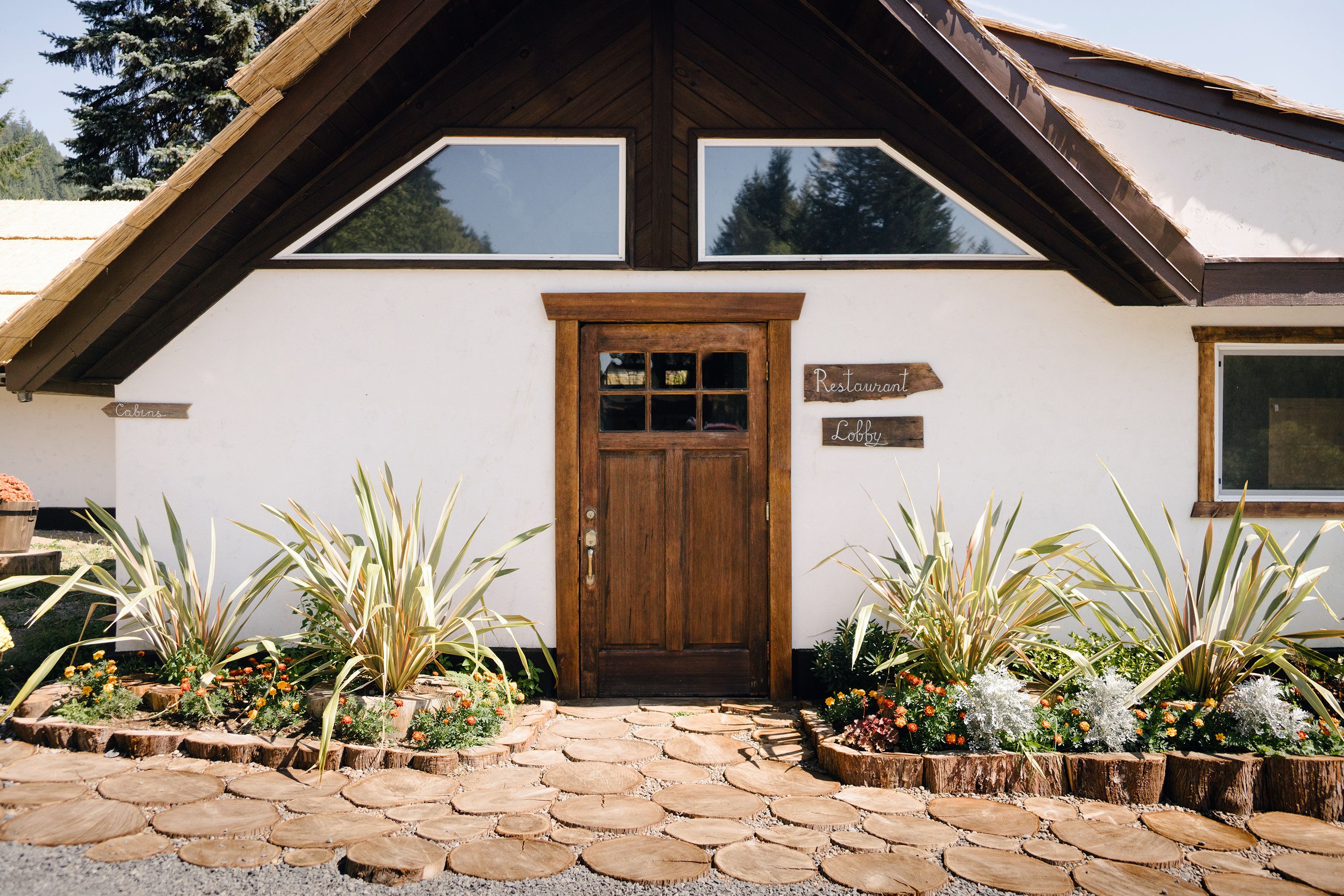 A building with a wooden door, a sign indicating a restaurant and lobby, and potted plants arranged in front.