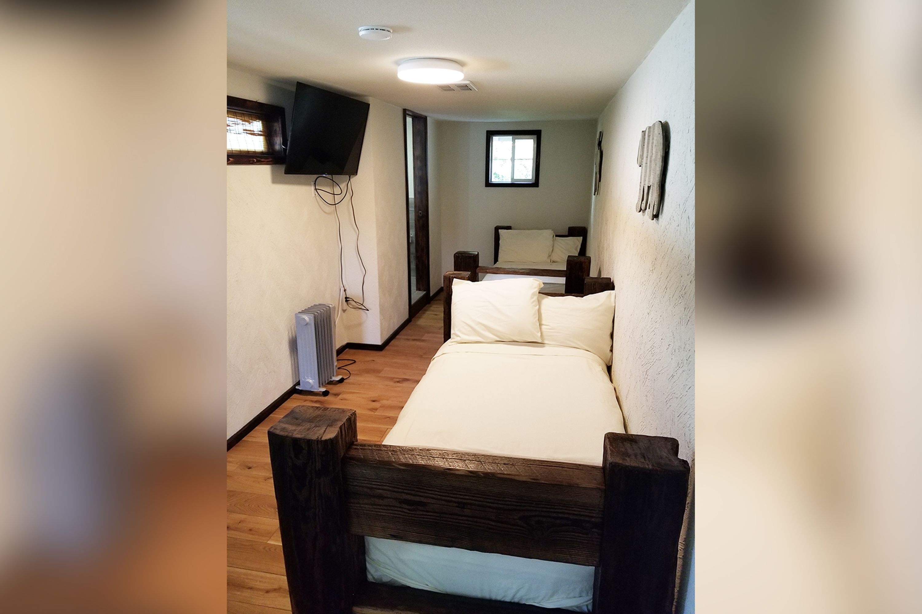Un dormitorio con cabecera de cama de madera, colchón blanco y una ventana pequeña.