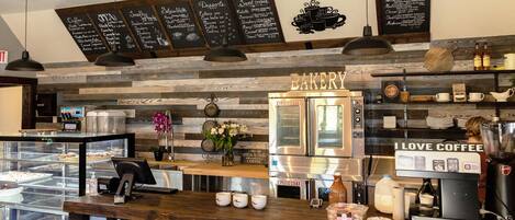 A bakery with a wooden counter, a coffee machine, and a display case with baked goods.