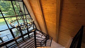 A wooden interior with a staircase and a large window overlooking a body of water. - Paradise Village Hotel (Ashford)