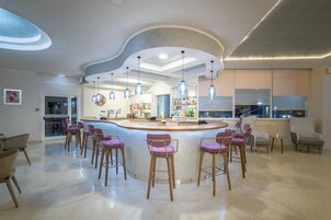Una cocina moderna con una isla curva, taburetes de bar, iluminación colgante y vistas a la ciudad.